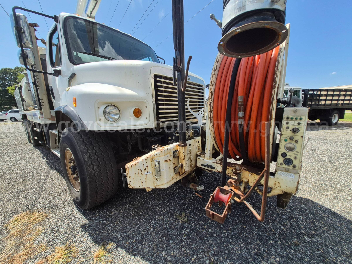 Freightliner M2 106V vacuum truck front-left view with large hose reel and reel controls.