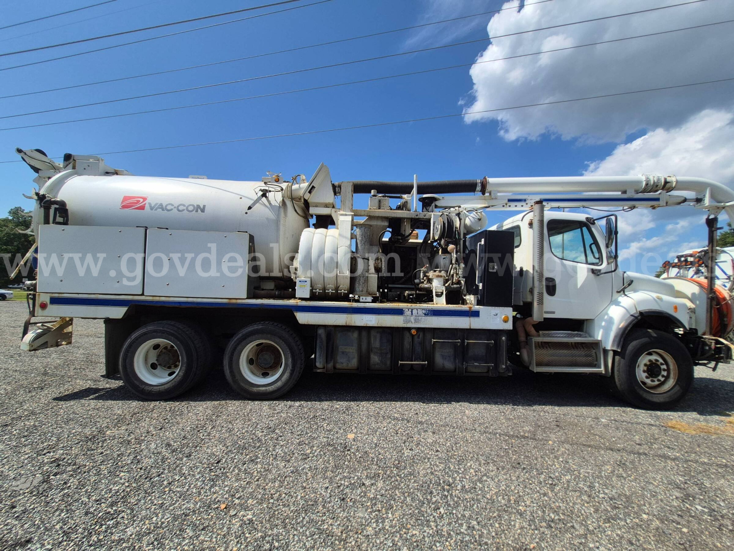 Truck-mounted vacuum unit on Freightliner M2 106V chassis with hose reel and vacuum tank, side view.