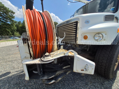 Freightliner M2 106V front view showing large orange hose reel and front bumper with chrome grille, white cab, and dual tires.