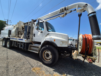 Freightliner M2 106V vacuum truck with a large hose reel on the side and a long elevated articulating boom. Cab shows front grille and headlights; side panels and wheel wells visible.