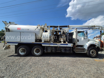 Truck-mounted vacuum unit on Freightliner M2 106V chassis with hose reel and vacuum tank, side view.