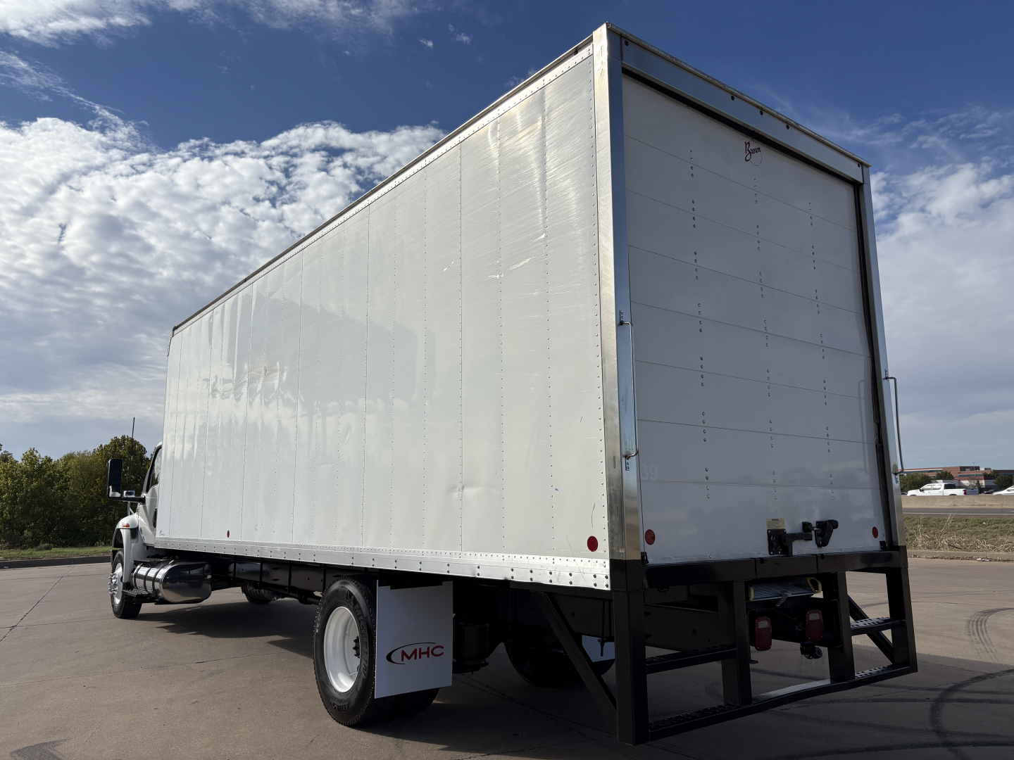 Box truck rear and side view showing white cargo area and black chassis, International MV607 with blank rear doors.