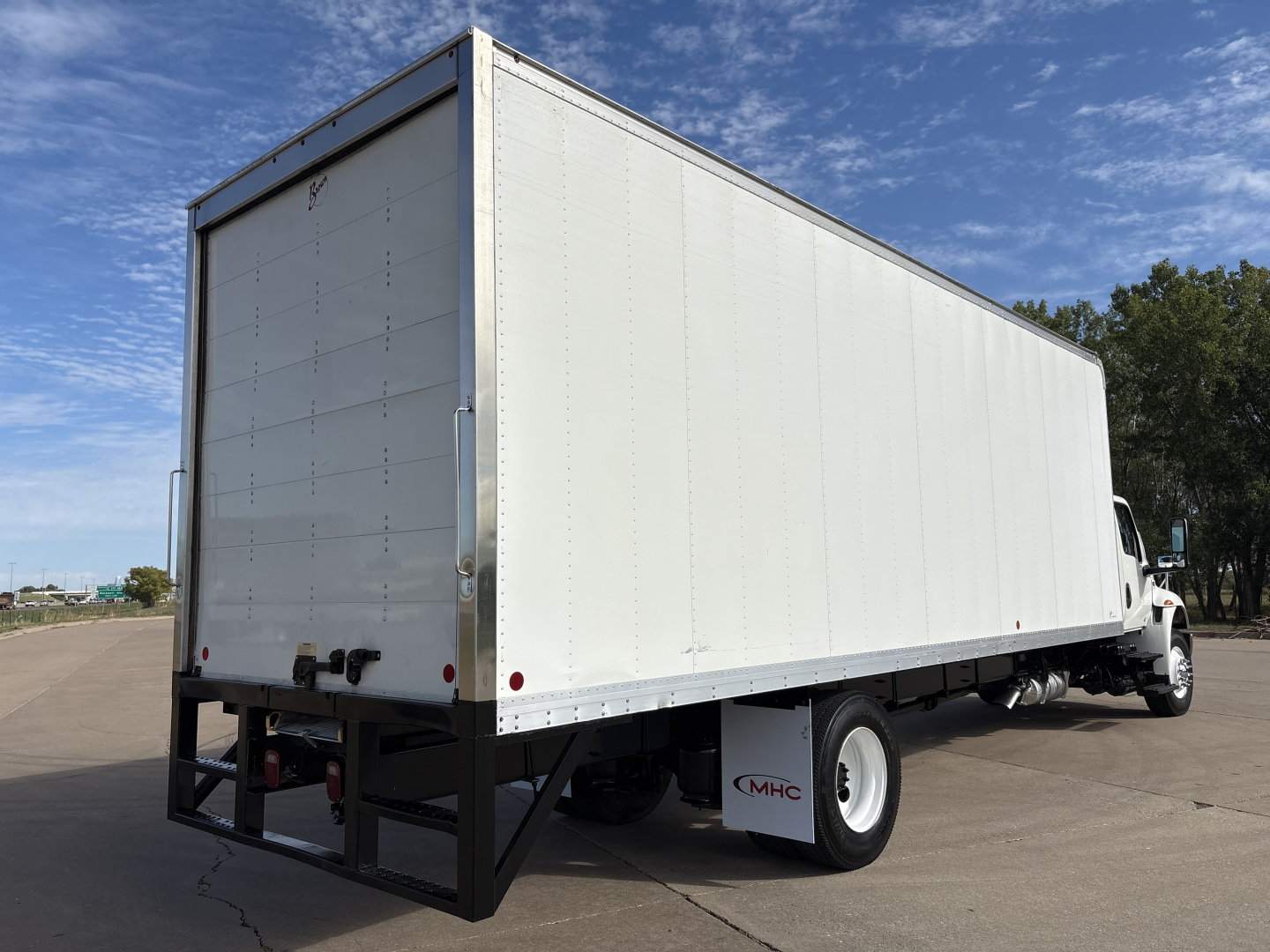 Box truck with white cargo area and black rear bumper viewed from left-rear angle showing MV607 box body and wheel wells.