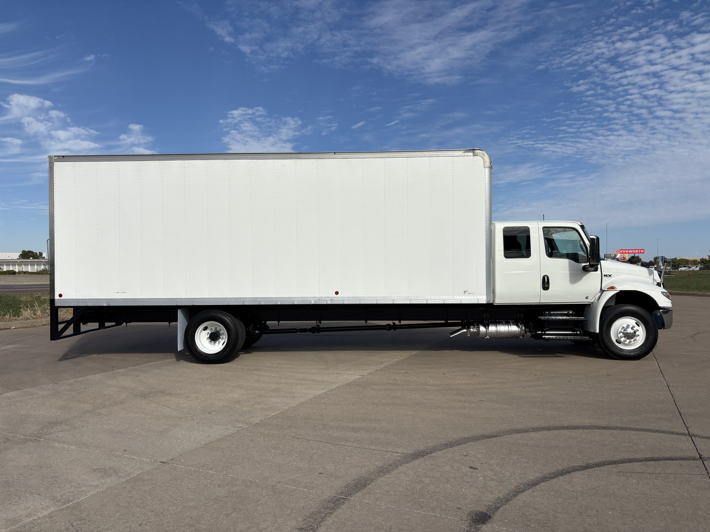 Box truck side view showing white cargo box and cab with International MV607 branding not visible.