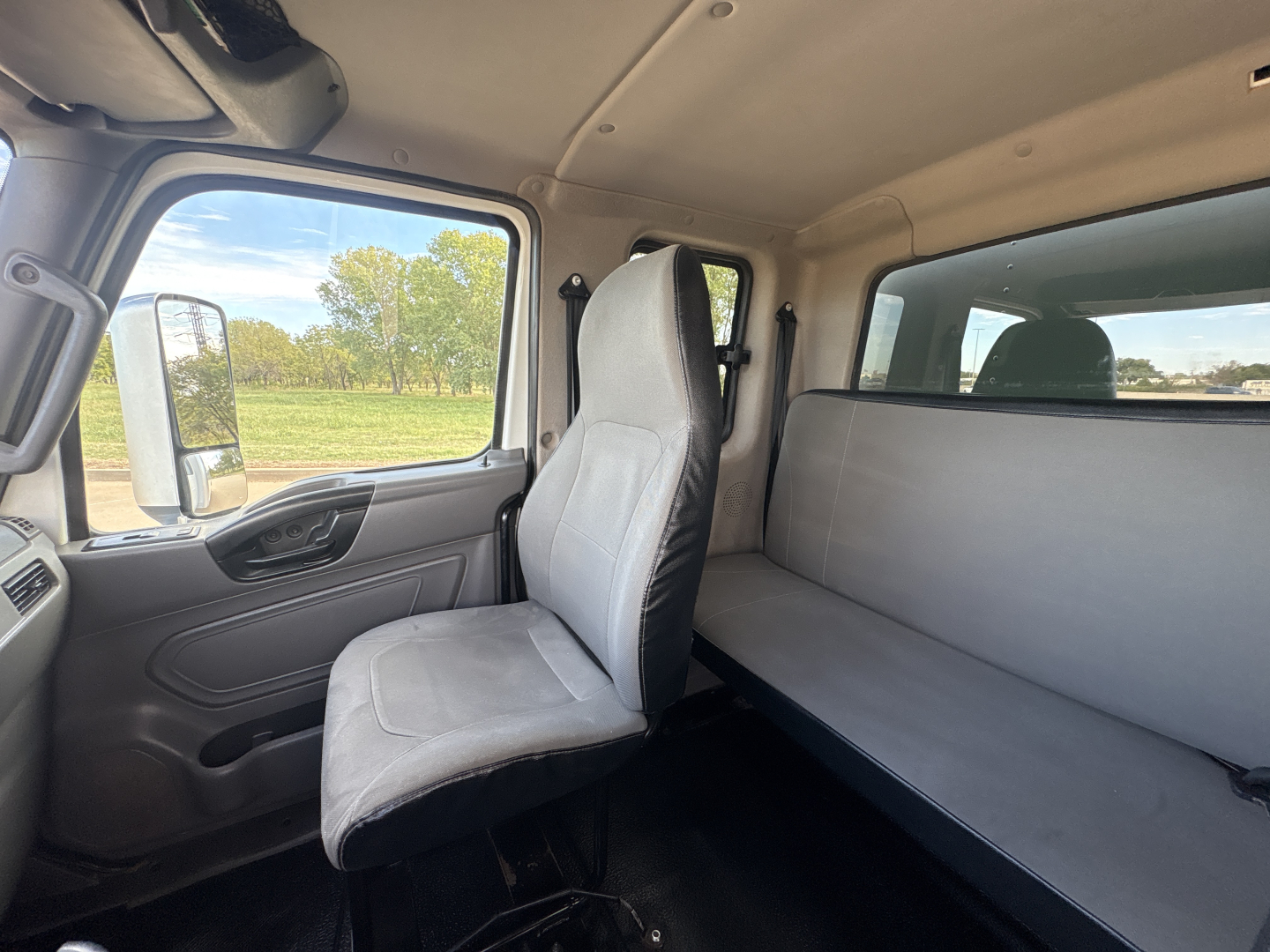 Interior of 2020 International MV607 cab with driver seat and sleeper bunk. Front window view, dashboard, door panel, and upholstered cab area visible.