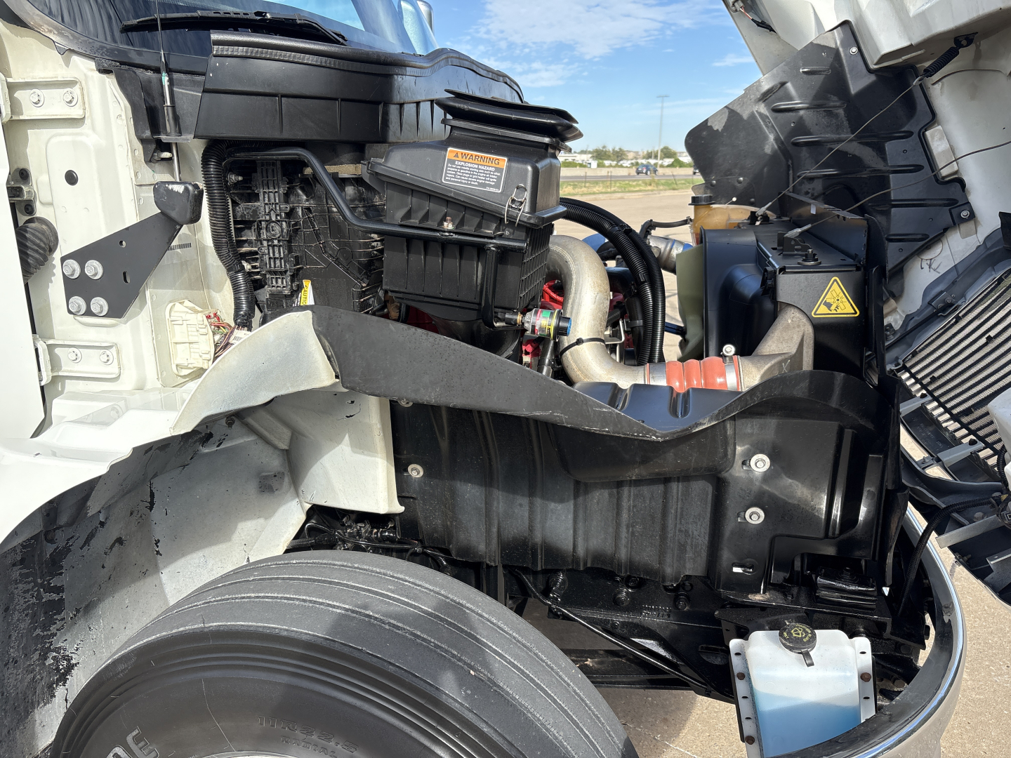 Truck engine bay of a 2020 International MV607 showing exposed components including air intake, coolant reservoir, and hoses.