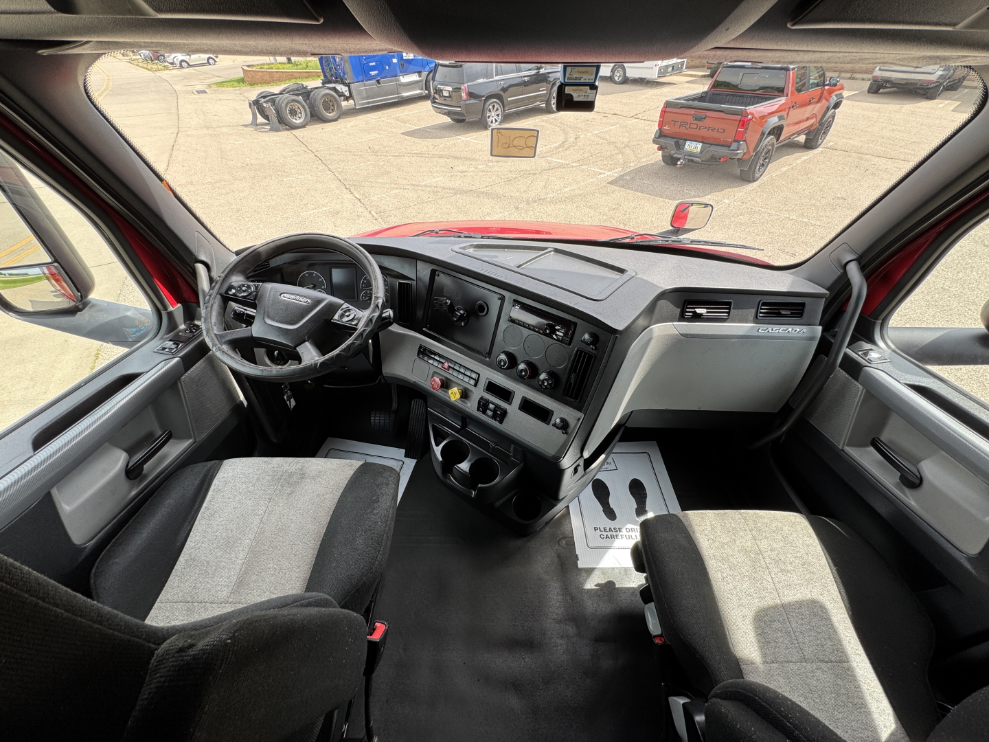 Conventional sleeper truck cab interior showing steering wheel, dashboard, and center console of a 2019 Freightliner Cascadia 126.