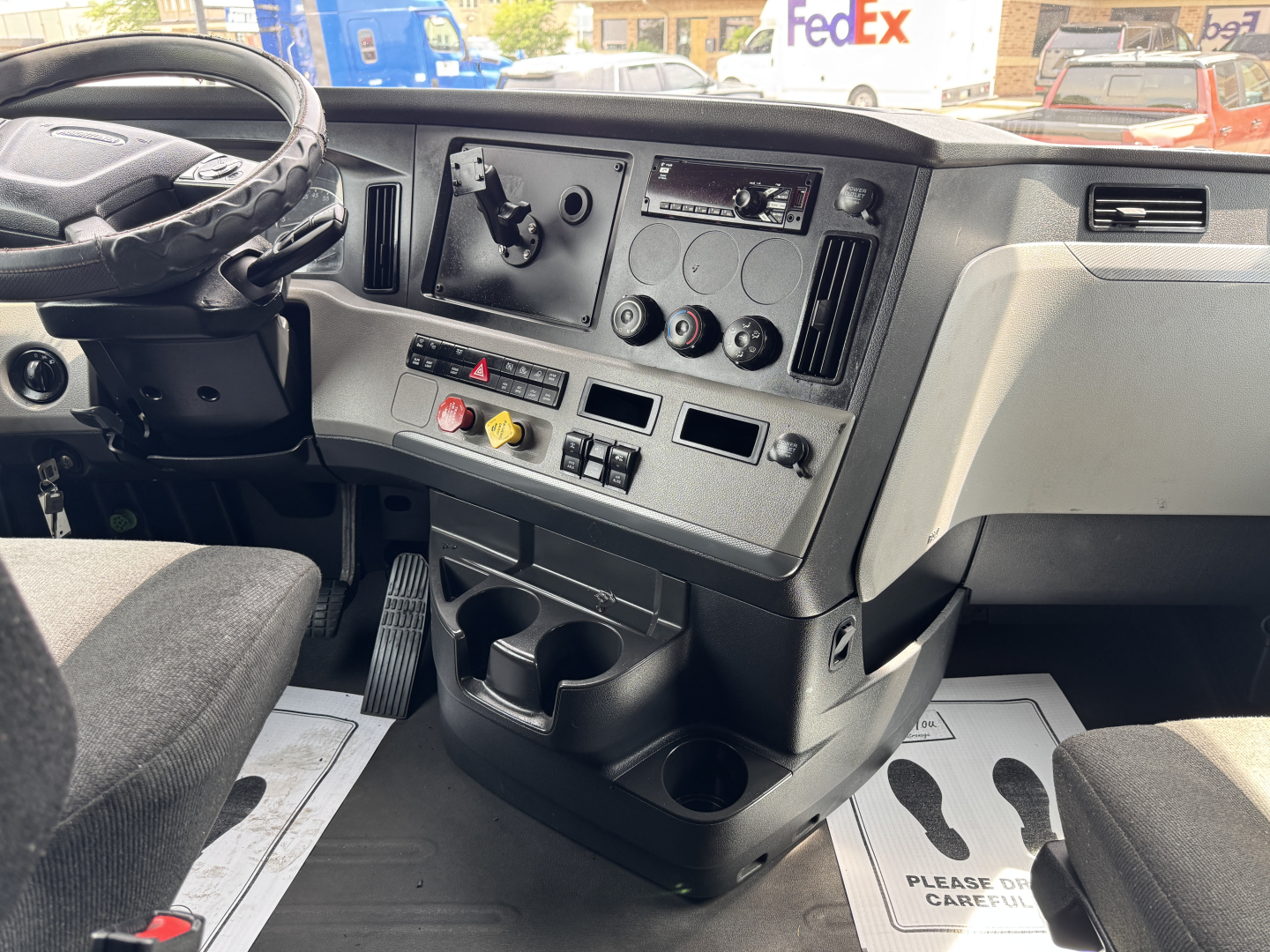 Dashboard of a 2019 Freightliner Cascadia 126 sleeper cab showing steering wheel, control panel with gauges, vents, climate controls, cup holders, and storage compartments.
