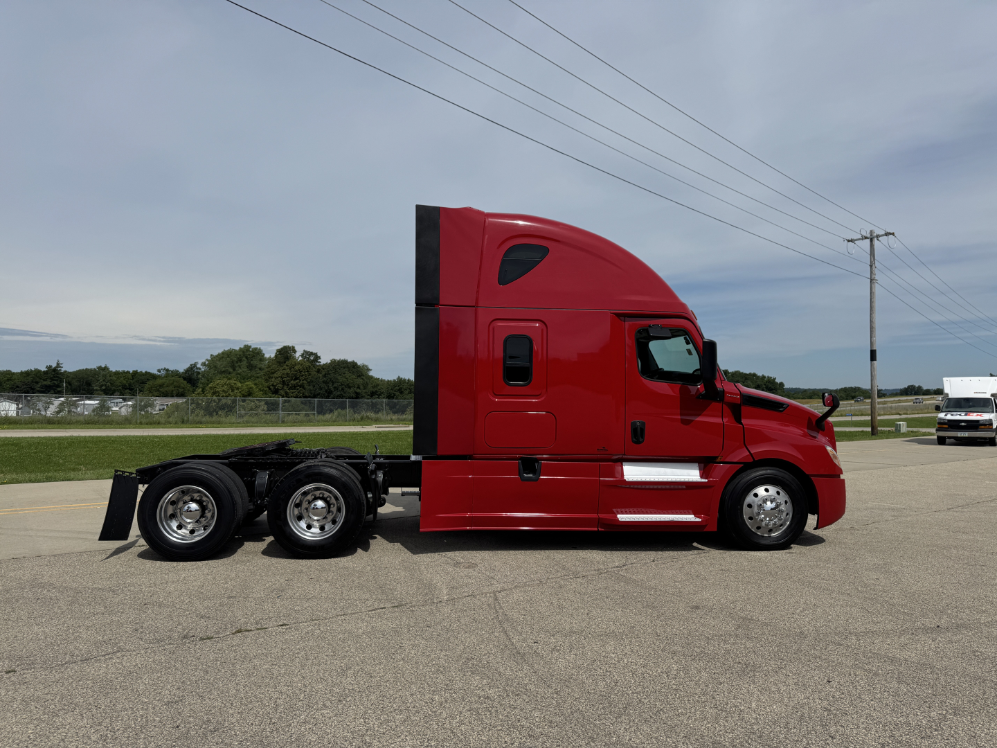 Truck side profile showing a red Freightliner Cascadia 126 sleeper cab tractor with triple rear axles and chrome wheels.