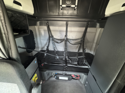 Freightliner Cascadia 126 sleeper cab interior rear bunk area with storage net and cargo strap system visible.