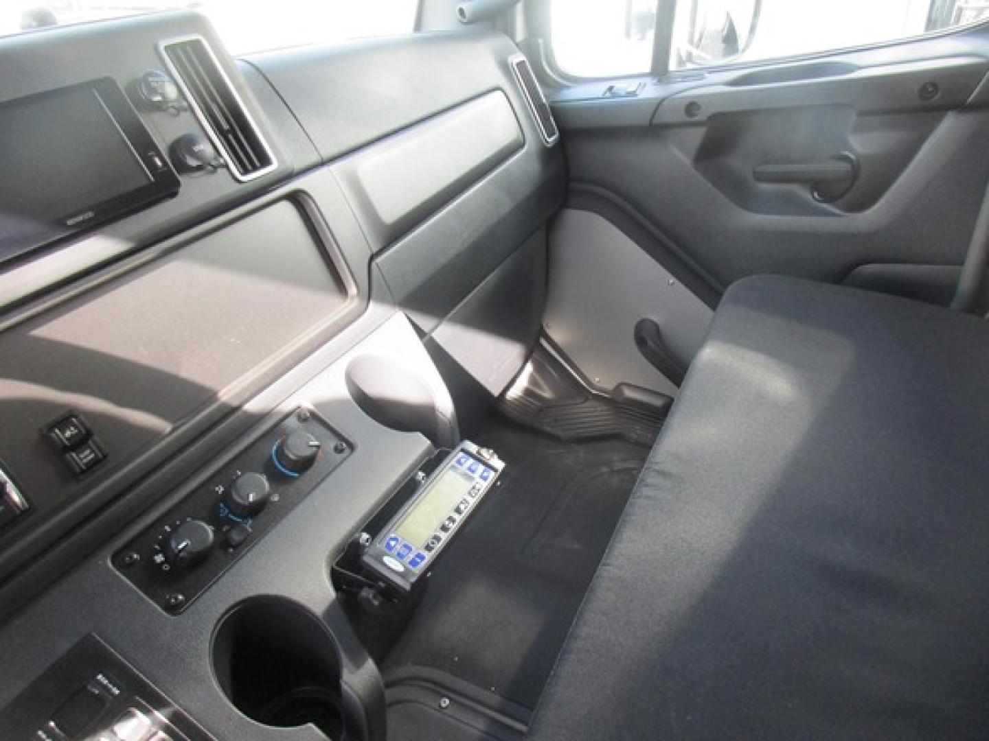 Freightliner M2 106 Plus cabin interior showing dashboard center controls and seating.