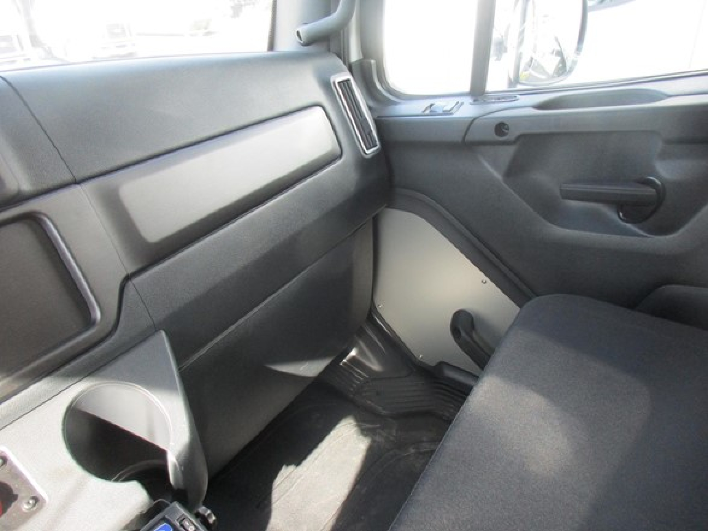 Freightliner M2 106 Plus interior passenger side showing dashboard and front door panel with cup holder and clean fabric seat.