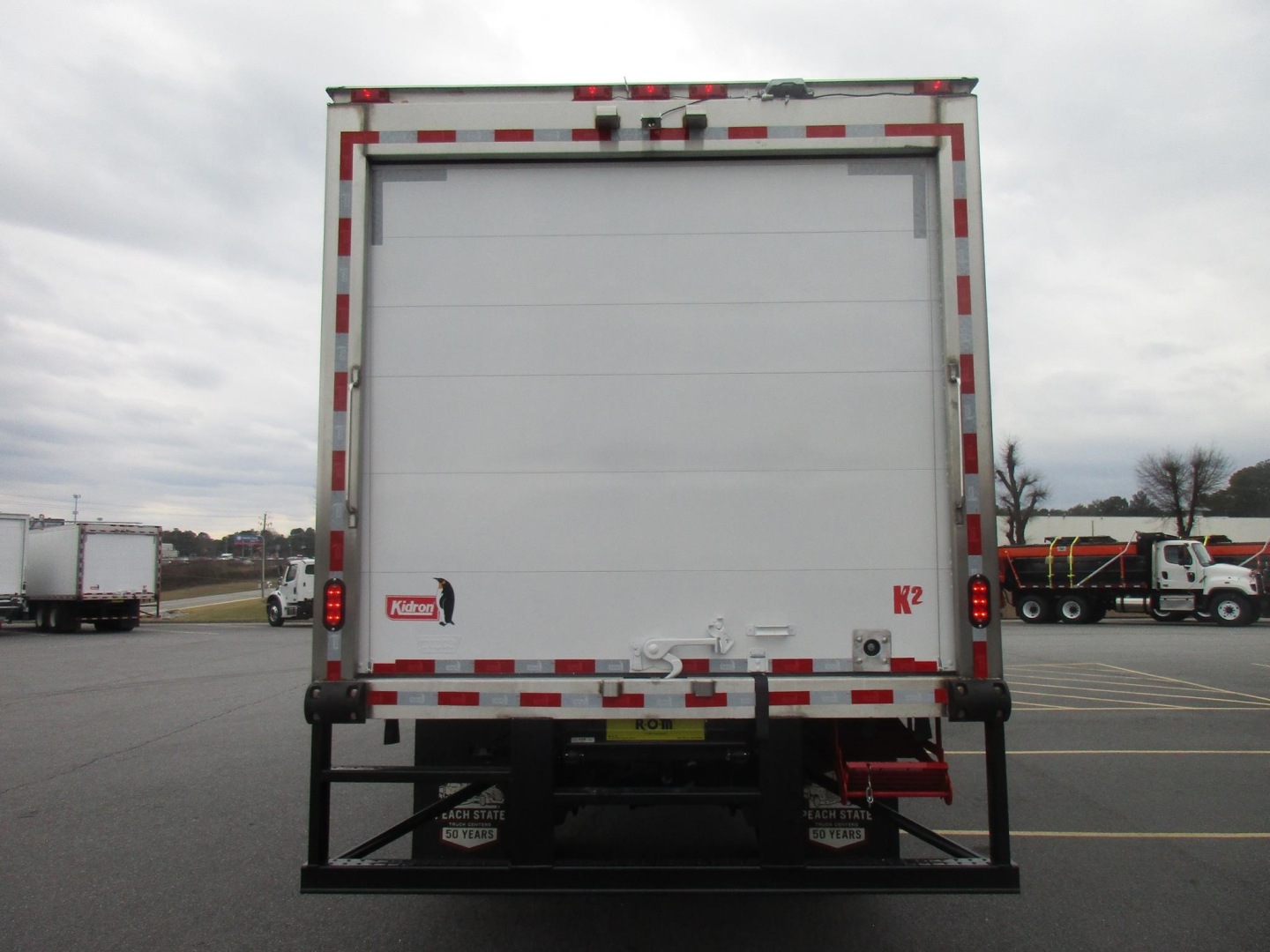 Freightliner M2 106 Plus rear view showing white box refrigerated body and bumper guard.