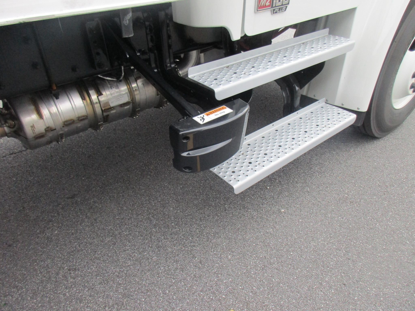 Freightliner M2 106 Plus side steps and fuel tank area visible under cab with metallic perforated steps.