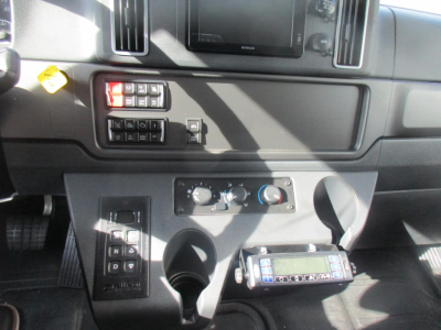 Freightliner M2 106 Plus cab interior showing dashboard controls, climate knobs, cup holders, and radio unit.