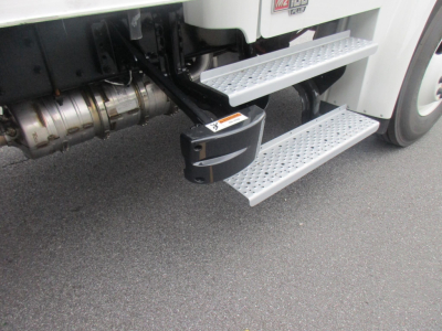 Freightliner M2 106 Plus side steps and fuel tank area visible under cab with metallic perforated steps.
