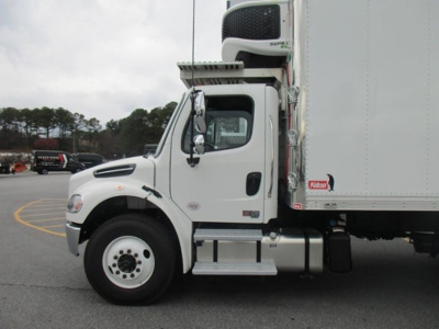 Freightliner M2 106 Plus refrigerated truck side view showing cab and cargo box with refrigeration unit on top and storage tanks beneath the cab.