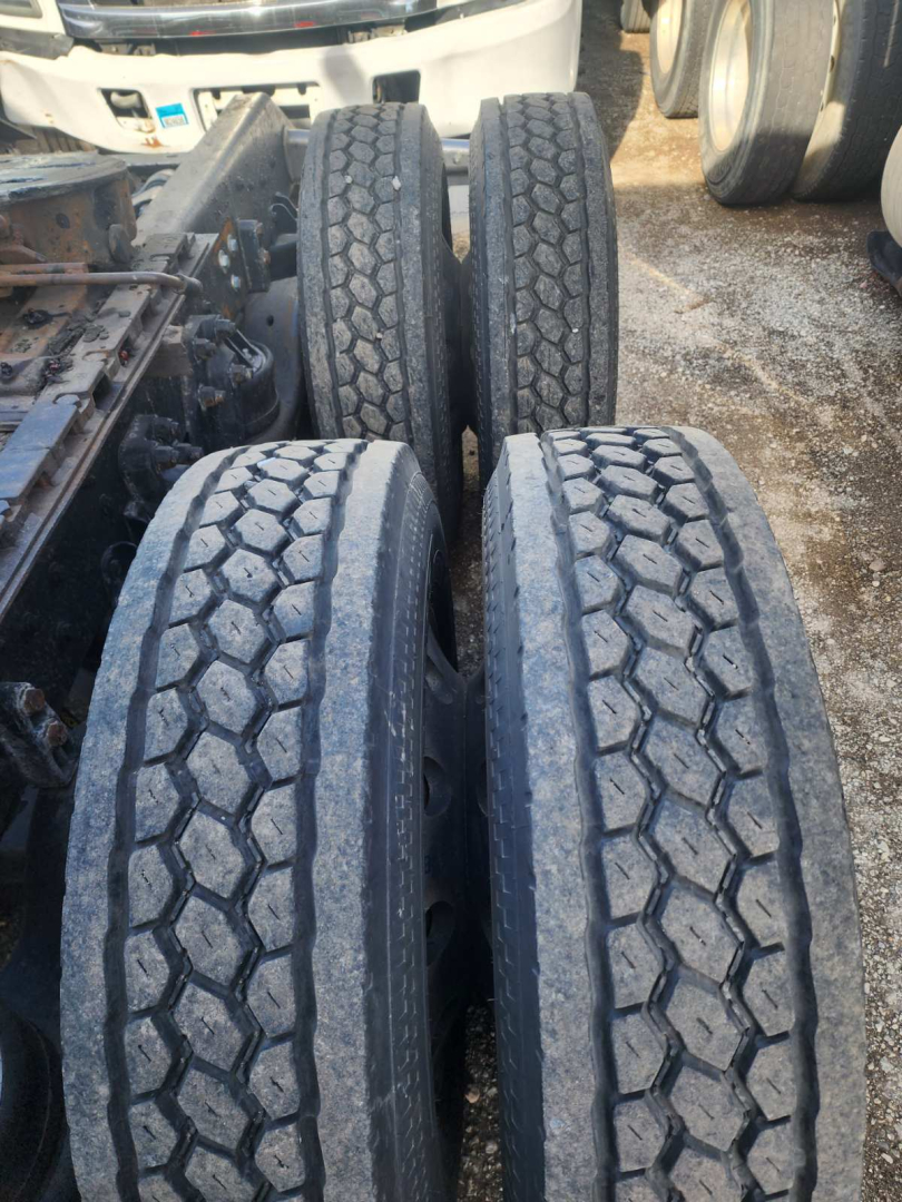 Truck wheelset showing four dual rear axles with treaded tires and part of chassis; no visible text readable.