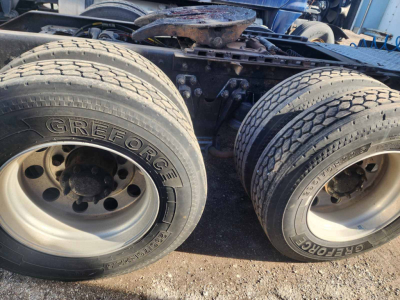 Dual rear wheels of a Kenworth truck showing Gre Forgett? brand tires and axle hub; chassis frame and fifth wheel visible.