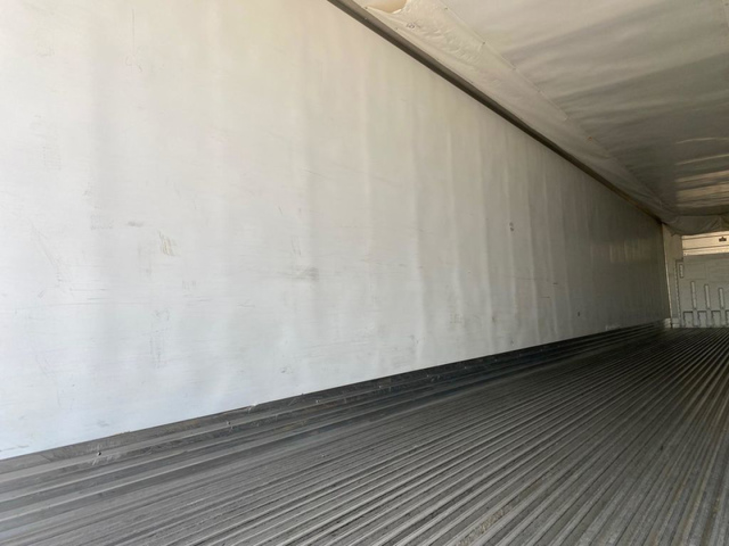 Interior of a 2021 utility reefer trailer showing metal non-slip floor and side walls with a distant door at rear.