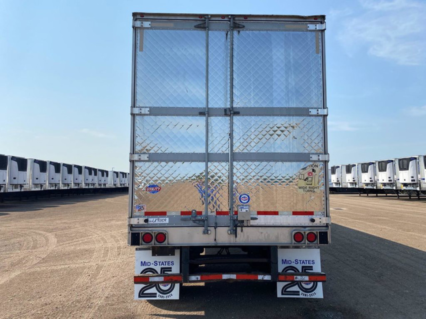 Trailer rear view of a 2021 refrigerated utility trailer with diamond plate doors, metal frame, and bumper with mud flaps and company decals.