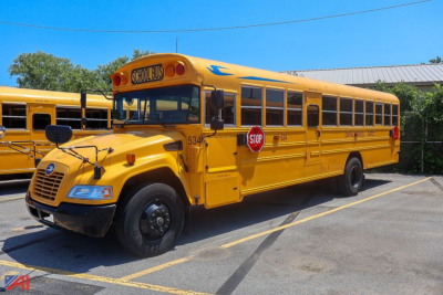 School bus with yellow body and blue trim, front grille, stop sign extended, number 5343 on door near front, and 'SCHOOL BUS' sign on top front.