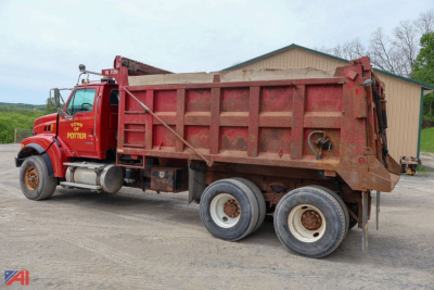 Dump truck showing red Sterling LT9500 dump truck side view with multiple rear axles and dump bed.