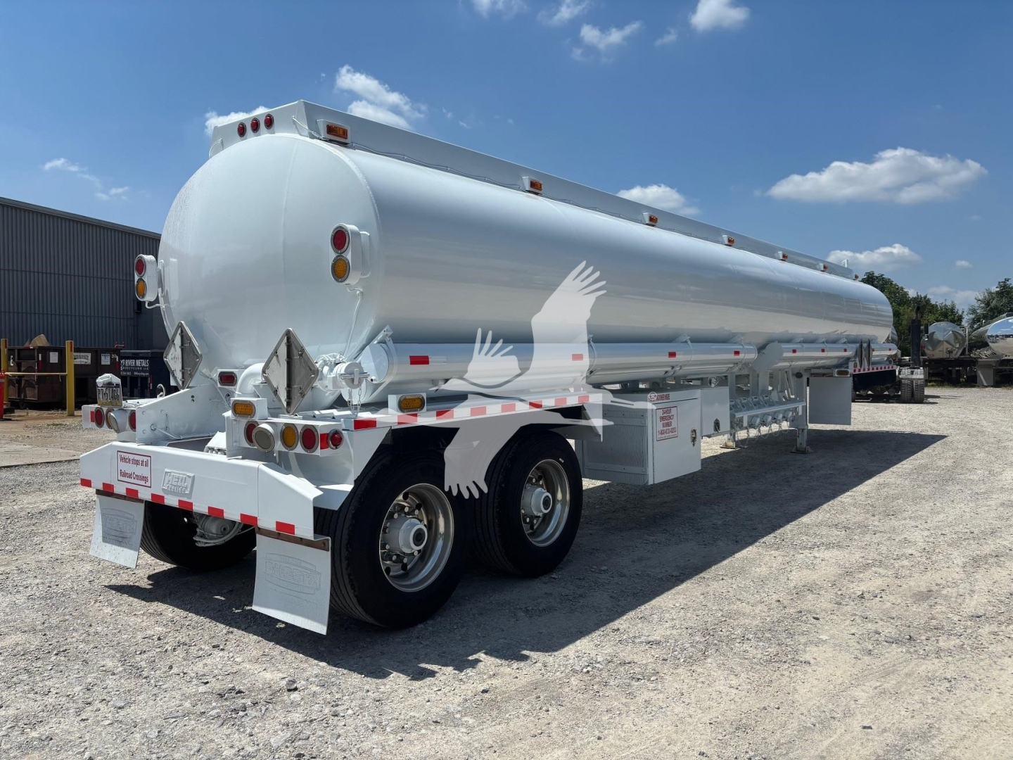 Haul trailer showing a cylindrical aluminum tank mounted on a double-axle trailer chassis with rear diamond plate and safety markings.