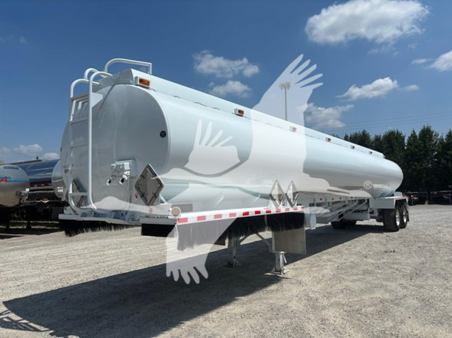 Tandem-axle tanker trailer showing cylindrical white DOT406 fuel tank with ladder, reflective tape, and stabilizing landing gear under bright sky.