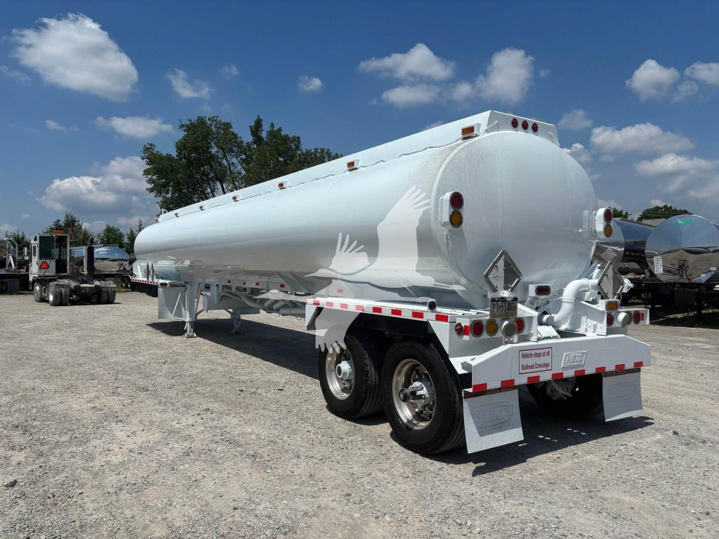 2020 Heil 9200 tanker trailer with white paint, dual rear axles, and safety reflectors. Tank features side ladders, rear bumper with hazard placards, and multiple lights.