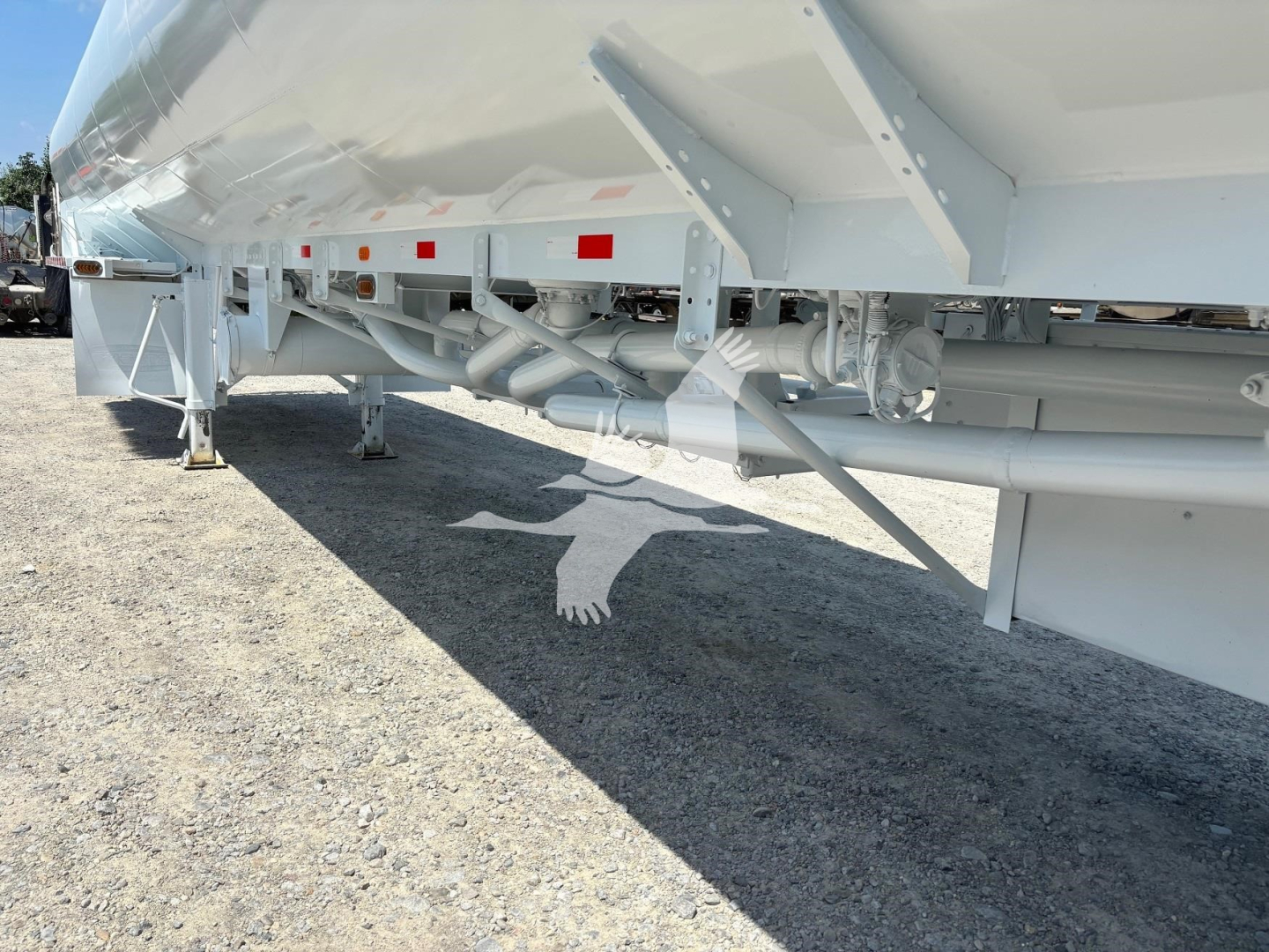 Trailer undercarriage showing dual axles, piping, frame rails, and support legs of a Heil 9200 trailer.