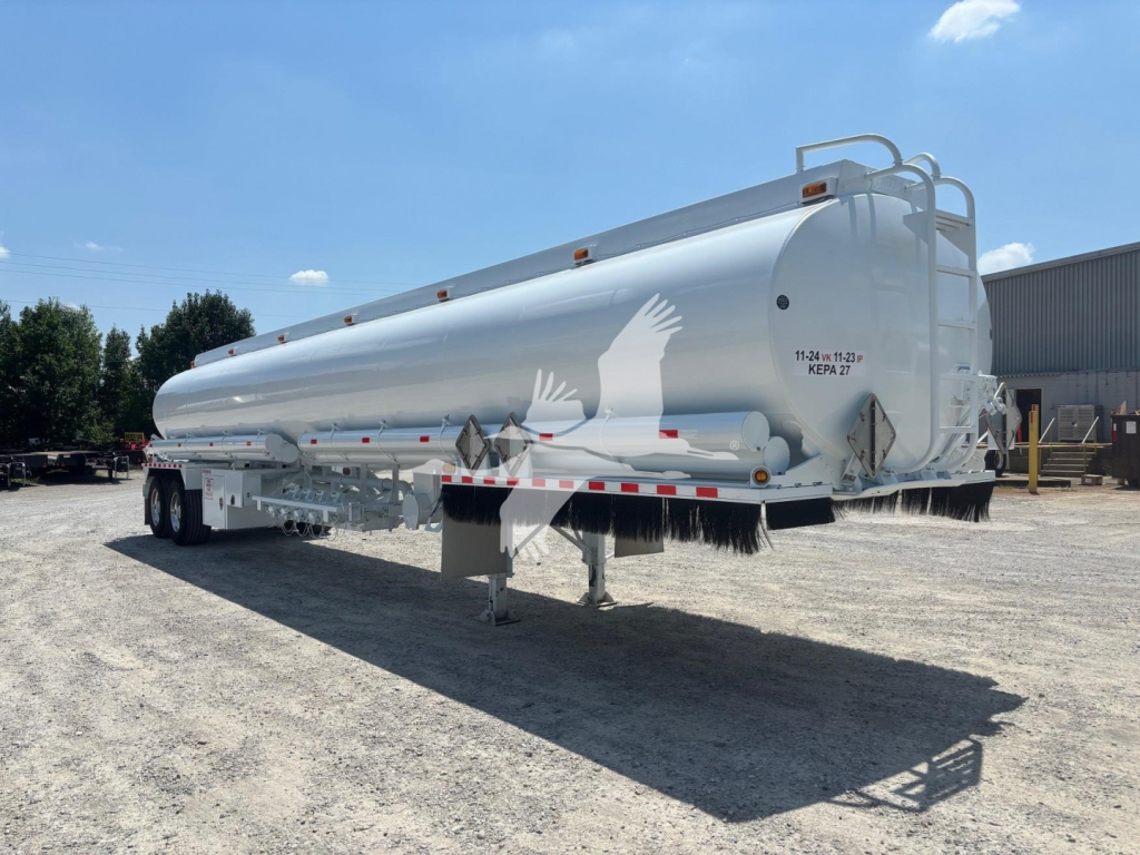 Rear and side view of a white Heil 9200 tanker trailer showing warning placards, rear ladder, and support legs.