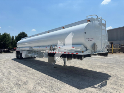 Rear and side view of a white Heil 9200 tanker trailer showing warning placards, rear ladder, and support legs.