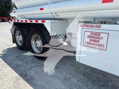 Truck trailer showing dual rear wheels and a white rectangular compartment with a red 24-hour emergency number sign reading "FIRE EXTINGUISHER INSIDE" and contact number. Steel compartments and reflective tape along side.