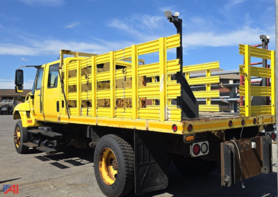 International SA515 WorkStar stake bed truck with bright yellow side rails and loading deck, rear view showing dual rear wheels and stake bed posts.
