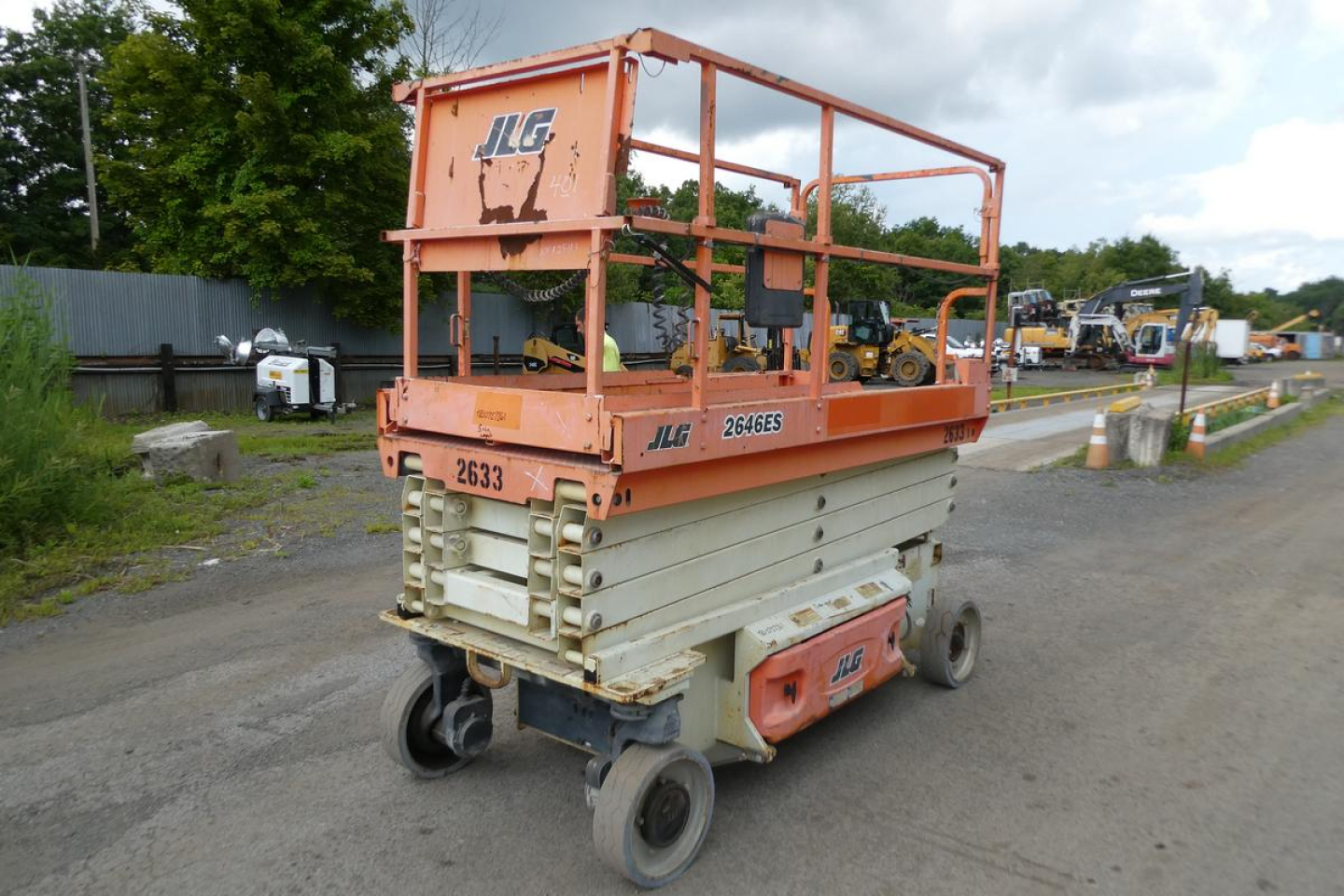 JLG 2646ES scissor lift side/back view showing orange guard rails, gray scissor mechanism, and wheels.