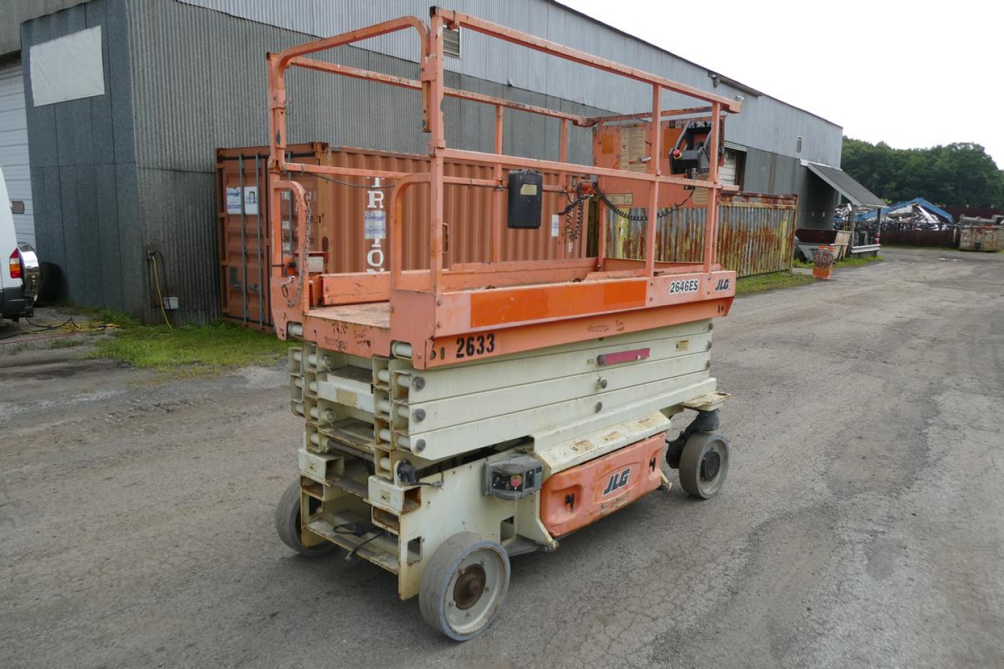 JLG 2646ES scissor lift in service position with orange upper frame and white lower base, viewed from rear-left side.