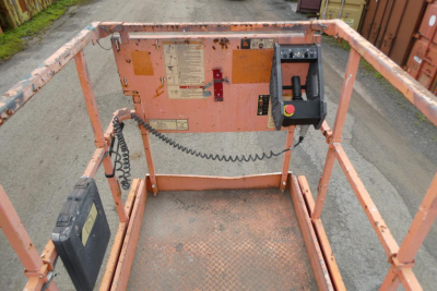 JLG 2646ES scissor lift control panel and platform edge with labels and control switches visible.