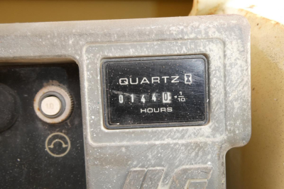 Quartz hour meter reading 01440 .1? hours on control panel of JLG 2646ES scissor lift with faded display and surrounding worn panel.