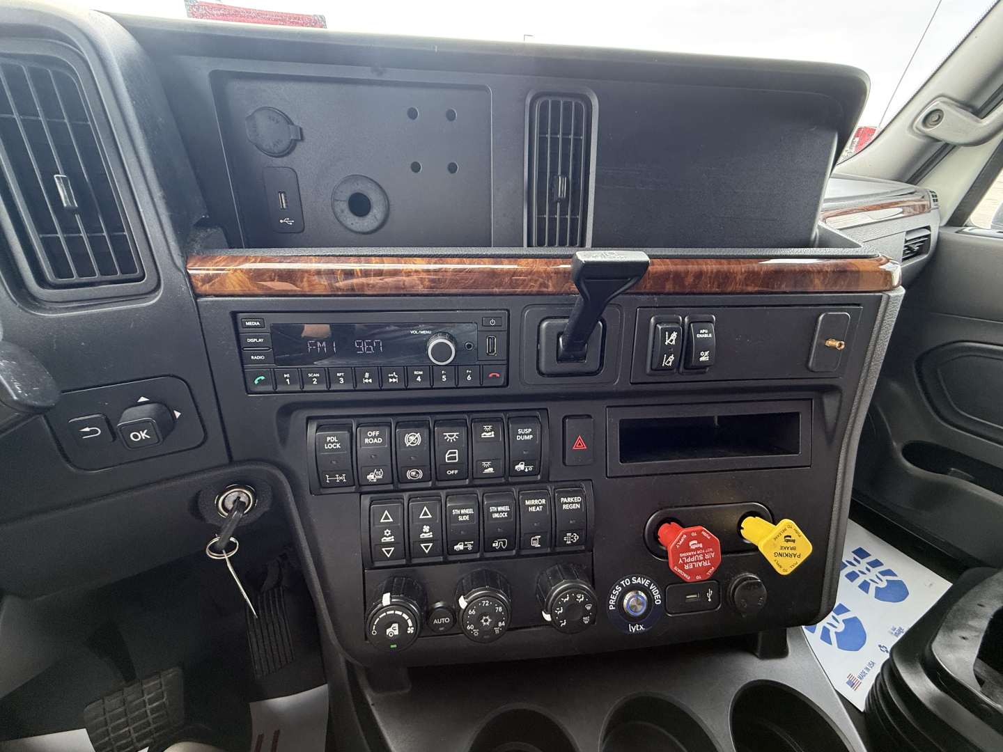 Dashboard area of a 2022 International LT625 cab showing climate controls, radio, and various switches with woodgrain trim.