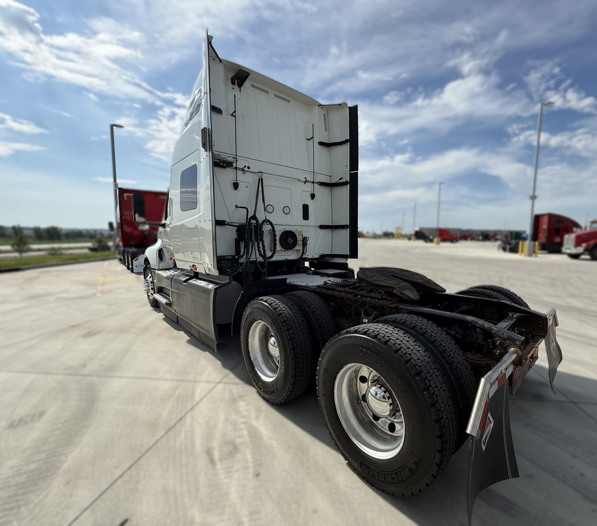 Truck cab and chassis of a 2022 International LT625 in a parking lot; side and rear views show fuel tanks and wheel wells.