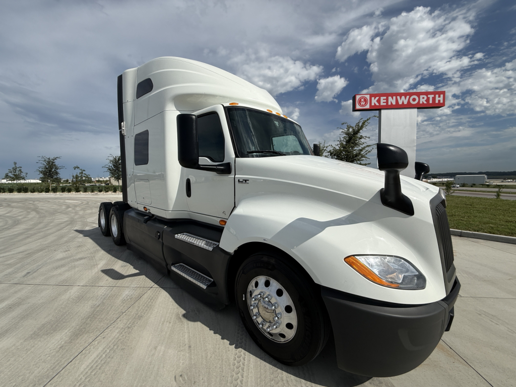 Truck in a lot showing International LT cab and Kenworth background. Visible text includes Kenworth sign and LT badge on the side.