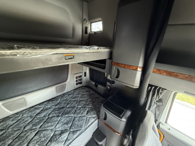 Interior of a 2022 International LT625 sleeper cab showing upper bunk area and dashboard with wood trim accents.