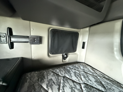 Cabin interior of a 2022 International LT625 sleeper showing a bunk bed area with patterned mattress, window shade panel, and storage recess.