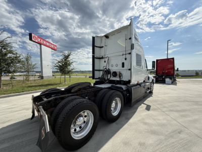 International LT625 truck at roadside showing rear tractor and dual rear axles with fifth wheel, sleeper cab, Kenworth sign in background.