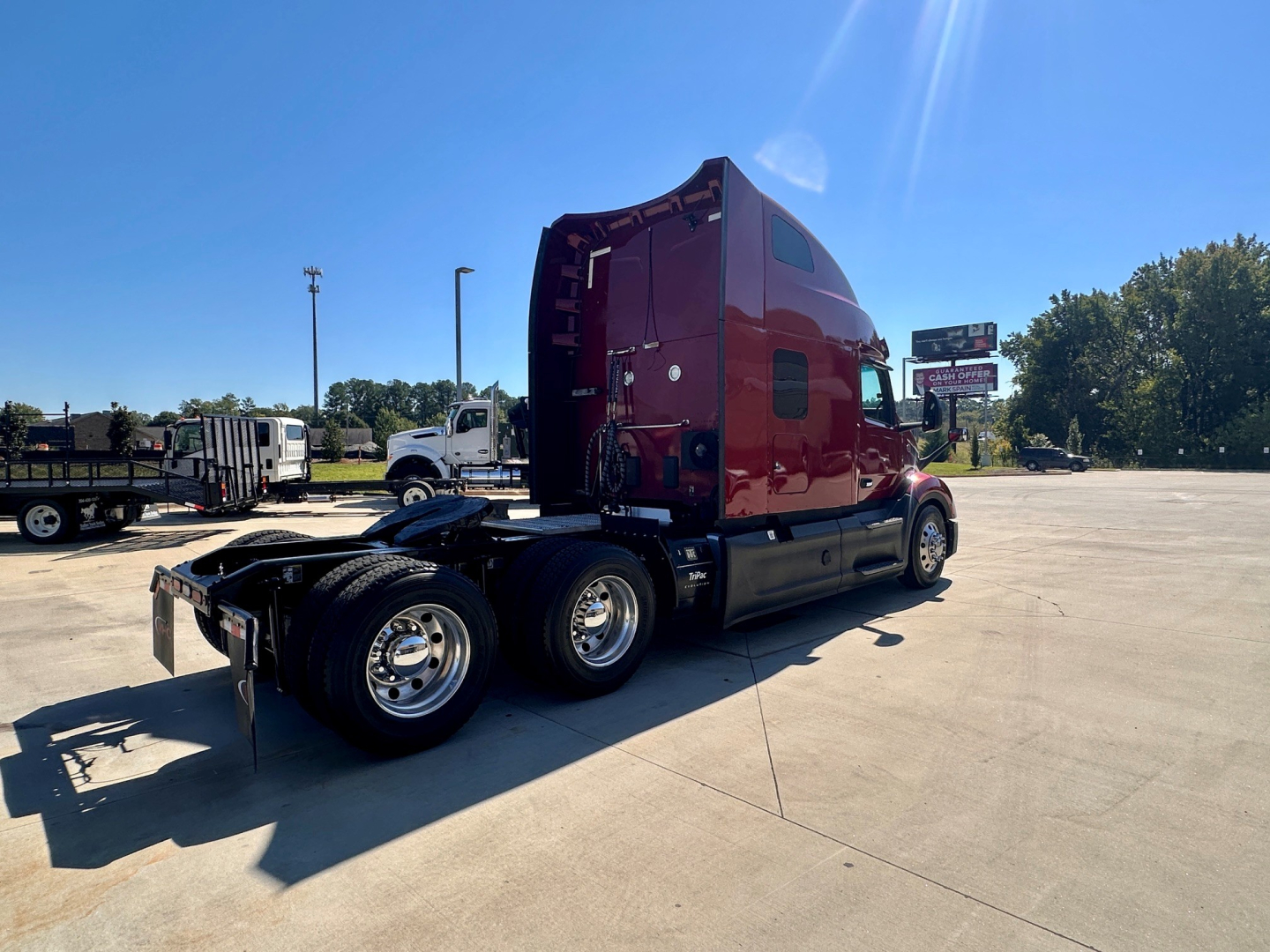 Peterbilt 579 sleeper cab tractor from rear 3/4 angle showing burgundy exterior, dual rear axle, and chrome wheels.