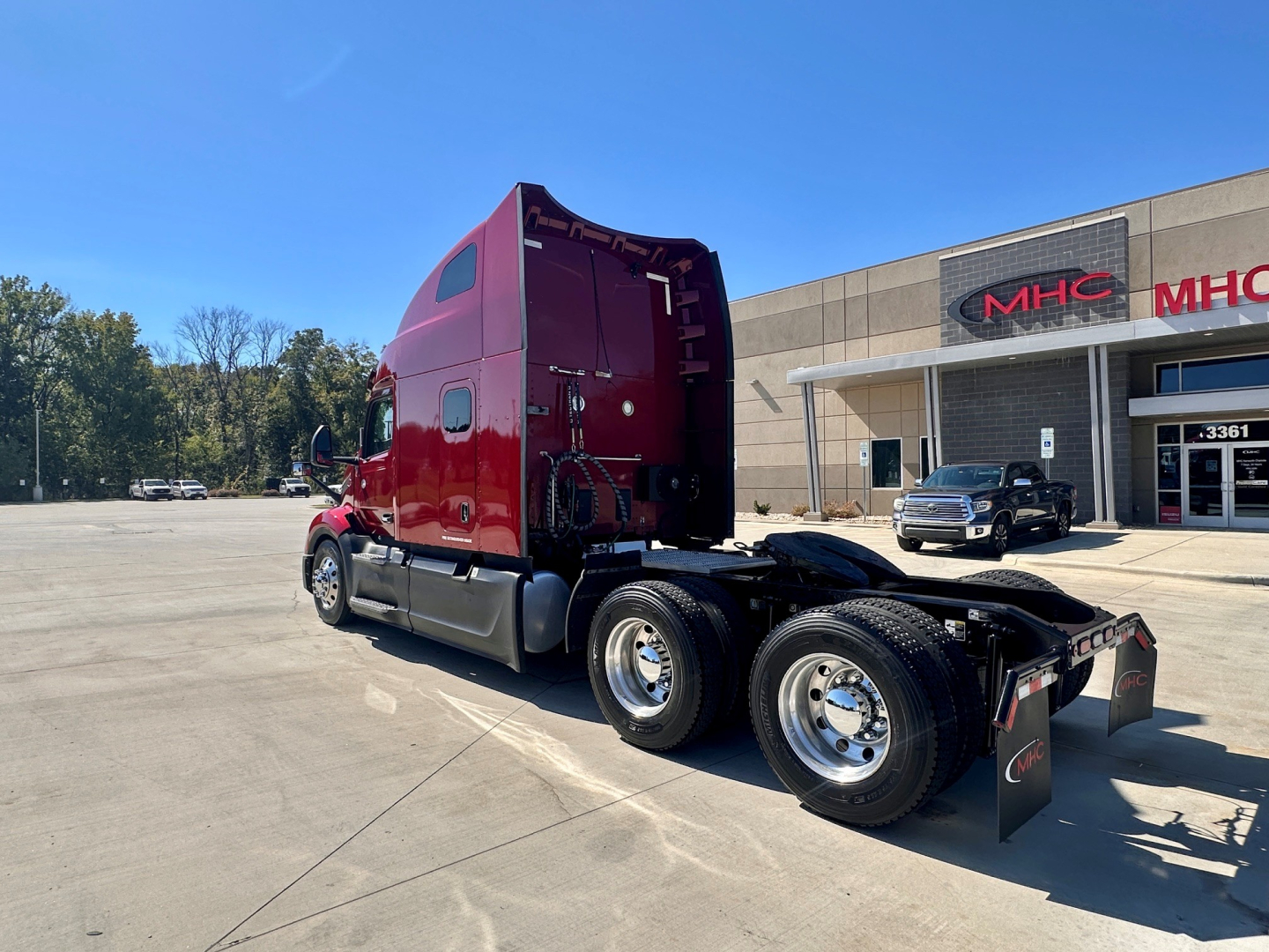 Peterbilt 579 tractor cab with red exterior, rear view showing fifth wheel and dual rear axles in a dealership lot.