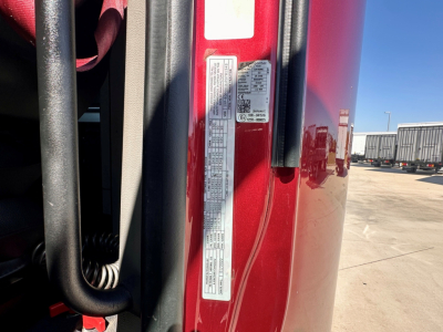 Peterbilt 579 door jamb with multiple specification labels and VIN sticker visible on the red truck frame.