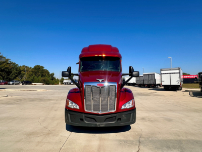Peterbilt 579 truck front view in red with chrome grille and large black bumper, daytime outdoor lot.