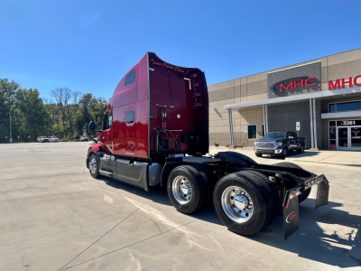 Peterbilt 579 tractor cab with red exterior, rear view showing fifth wheel and dual rear axles in a dealership lot.